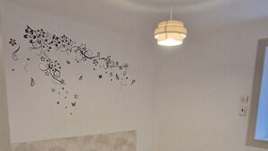 A room with two single beds, a ceiling light, and a wall decoration. - Gîte near Puy du Fou (Montournais)