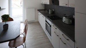 A modern kitchen with white cabinets, a black countertop, and a built-in oven. There is a window with a view of buildings outside.