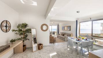 A spacious living area with a dining table set for four, a large mirror, and a potted plant.