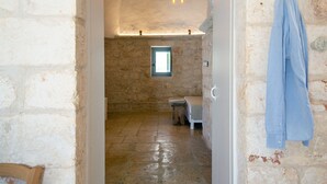 A stone-walled room with a bench, a small window, and a hanging light fixture. - Campanile Apartment With Terrace by Wonderful Italy (Ostuni)