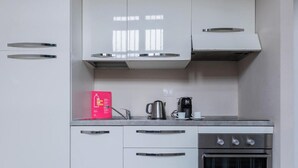 A modern kitchen with white cabinets, a stainless steel oven, and a coffee maker on the countertop. - Housing Giulia - Studio 2 4 by Wonderful Italy (Turin)