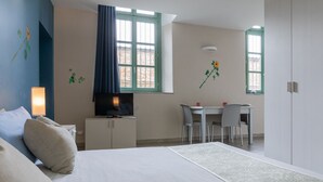 A bedroom with a bed, a TV, a desk, and two chairs. - Housing Giulia - Studio 2 4 by Wonderful Italy (Turin)