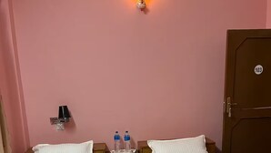 Une chambre d’hôtel avec deux lits, une table de chevet avec une lampe, deux bouteilles d’eau et une porte portant le numéro 103.
