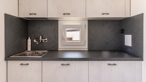 A modern kitchen with a built-in sink, a window, and a door leading to another room. - Aquamarine Terrace by Wonderful Italy (Syracuse)