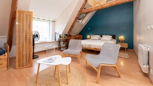 A bedroom with a sloped ceiling, a bed, two chairs, a table, a fan, and a radiator. - Embellie B&B – Guest Rooms with Shared Terrace, Garden & Wi-Fi (Baden)