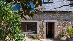 A stone building with a modern entrance, a window with blinds, and a potted plant in the foreground. - Embellie B&B – Guest Rooms with Shared Terrace, Garden & Wi-Fi (Baden)