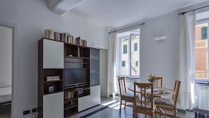 A modern living room with a large bookshelf, a dining table with chairs, and a view of the outside through a window. - A Un Passo Dalla Spiaggia di Camogli by Wonderful Italy (Camogli)