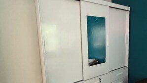 Een witte kast met meerdere lades en een spiegel.