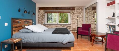 A bedroom with a bed, a window, a chair, a table, and a bookshelf.