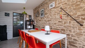 A dining area with a white table, red chairs, and a stone wall. - Voyage B&B with Shared Terrace, Communal Garden & Wi-Fi (Baden)