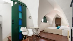 Una habitación pequeña con cama, una mesita y dos sillas.