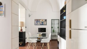 Una cocina moderna con armarios blancos, una mesa de comedor de vidrio y un cuadro en la pared.