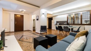 A modern living room with a sofa, ottomans, and a flat-screen TV. - Casa Ambrosini - Artemide Apt by Wonderful Italy (Bologna)