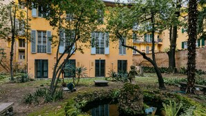A yellow building with multiple windows and shutters, surrounded by lush greenery and a small pond. - Casa Ambrosini - Artemide Apt by Wonderful Italy (Bologna)