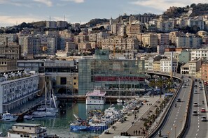 A marina with boats docked, a road parallel to the water, and buildings in the background. - Goletta Studio by Wonderful Italy (Genoa)