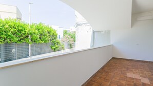 A balcony with a tiled floor, white walls, and a view of greenery and buildings. - Casa Pasquina by Wonderful Italy (Bari)