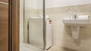 Een badkamer met een douchecabine van glas, een wastafel en een handdoekrek.