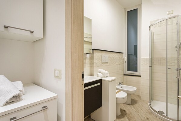 A modern bathroom with a shower, toilet, and sink.
