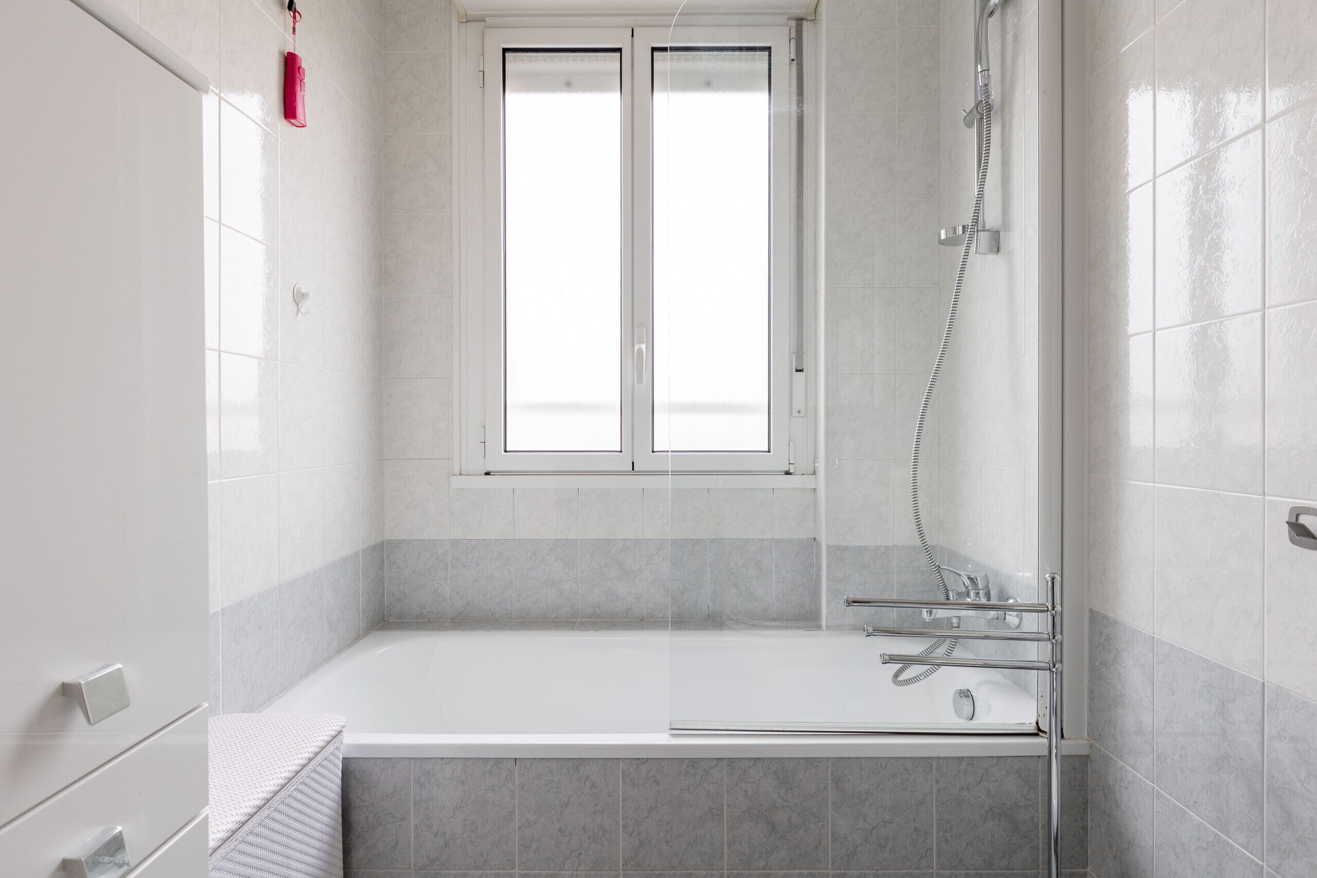 A modern bathroom with a bathtub, a shower, and a window.