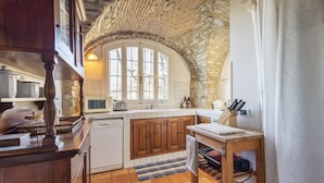 A kitchen with wooden cabinets, a stone ceiling, and a large window. - Traditional Ligurian House (Sanremo)