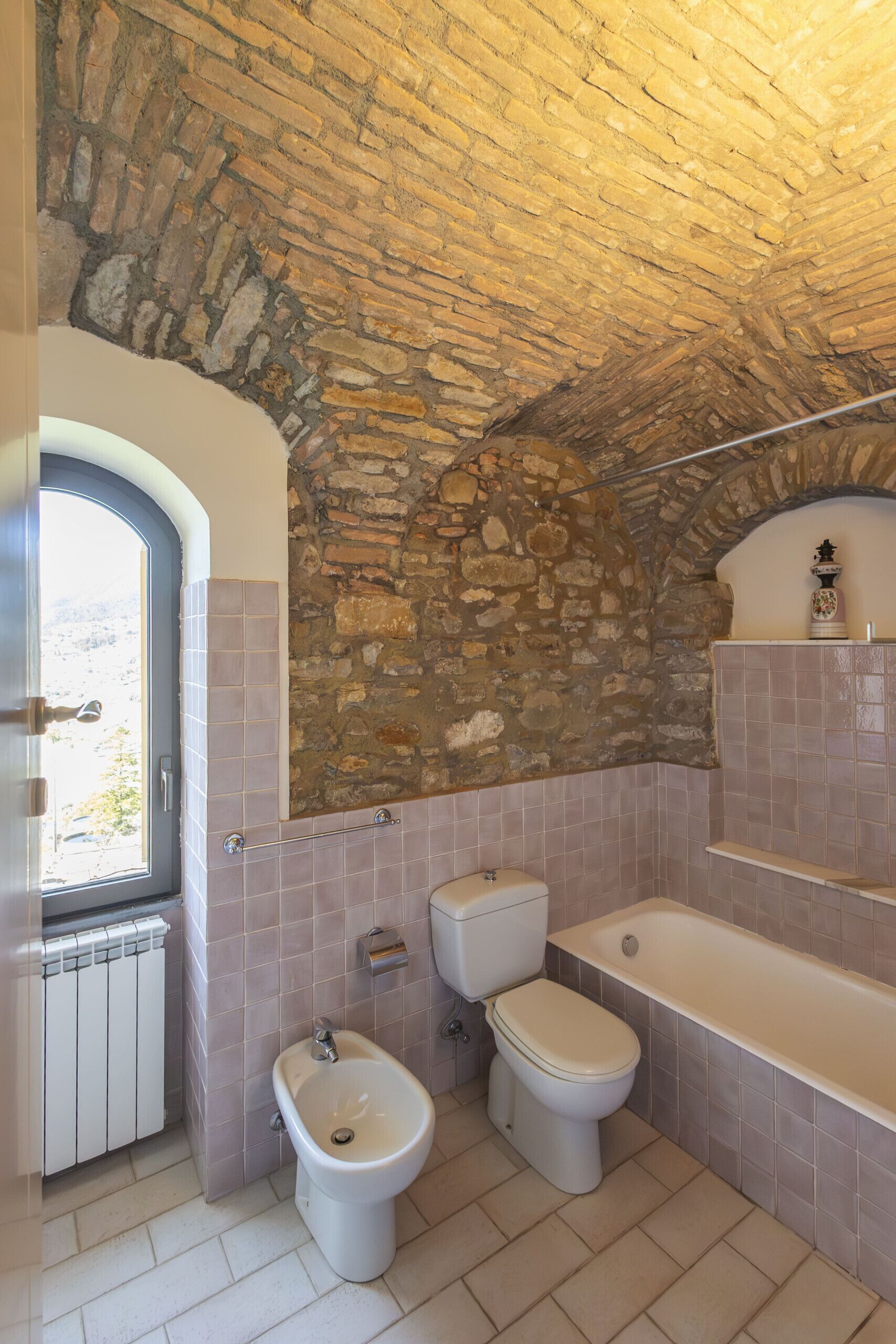 A bathroom with a stone ceiling, a bidet, a toilet, and a bathtub.