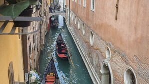 Un canal étroit où circulent des gondoles, bordé de bâtiments dotés d’arcades et d’une façade en briques.