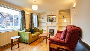 A living room with a green sofa, a red armchair, a wooden coffee table, and a fireplace. - Host & Stay | Riders Rest (Wootton)