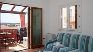 A room with a balcony, a sofa, a table with chairs, and a grill. - Casa Dello Chef by Wonderful Italy (Santa Teresa di Gallura)
