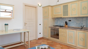 A compact kitchen with light wooden cabinets, a built-in oven, and a tiled backsplash. - Casa Dello Chef by Wonderful Italy (Santa Teresa di Gallura)