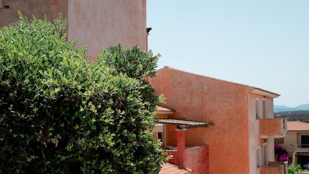 A residential building with a pink facade, a gated entrance, and a staircase leading to the upper floor. - Casa Dello Chef by Wonderful Italy (Santa Teresa di Gallura)