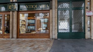 An antique shop with a wooden facade and large display windows. - Turin Bed Books by Wonderful Italy (Turin)