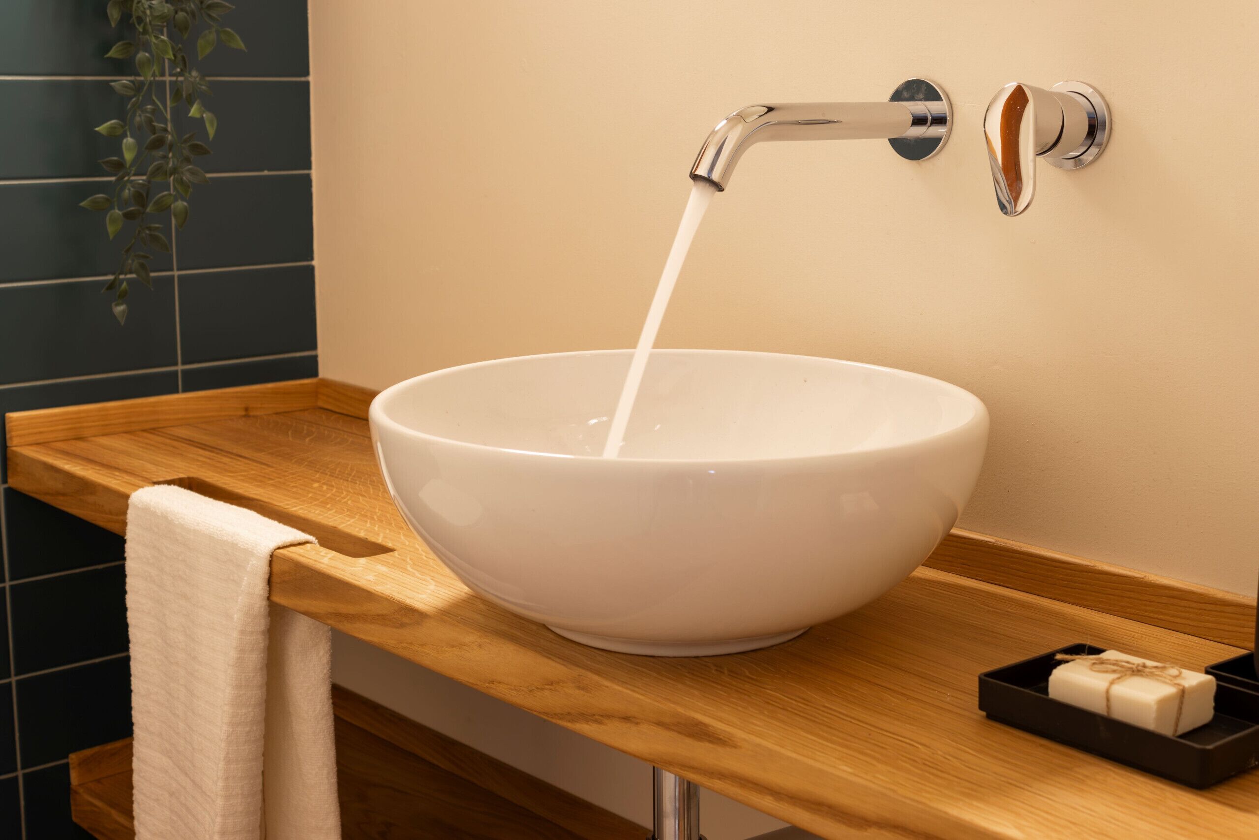 A white ceramic sink with a modern faucet, a wooden countertop, and a small soap dish.