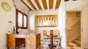 A room with a wooden desk, two chairs, a round table, a mirror, and a clock on the wall. - Ca di Malta Room 2 by Wonderful Italy (Venice)