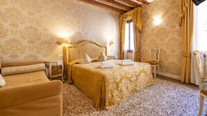 A hotel room with a large bed, a chair, a nightstand, and a lamp. - Ca di Malta Room 2 by Wonderful Italy (Venice)