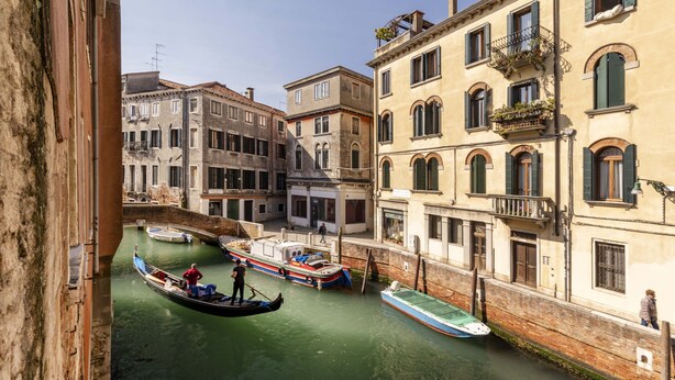 A canal with gondolas and boats, buildings with balconies, and a bridge in the background. - Ca di Malta Room 1 by Wonderful Italy (Venice)