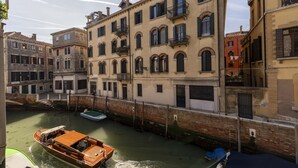 A canal with boats, historic buildings, and a wooden boat with a canopy. - Ca di Malta Room 1 by Wonderful Italy (Venice)