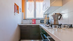 A compact kitchen with a window, a microwave, a coffee maker, and a sink. - Torino Lifestyle Apartment by Wonderful Italy (Turin)