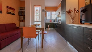 A compact living space with a dining area, kitchenette, and a red sofa. - Torino Lifestyle Apartment by Wonderful Italy (Turin)