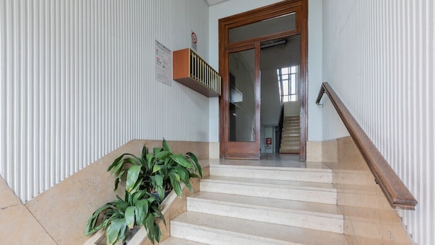 A staircase with a wooden handrail, beige steps, and green plants at the bottom. - Torino Lifestyle Apartment by Wonderful Italy (Turin)