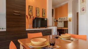 A modern kitchen with a dining table set for two, featuring a flat-screen TV above the counter and decorative wall art. - Torino Lifestyle Apartment by Wonderful Italy (Turin)