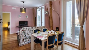 Un comedor con una mesa dispuesta para cuatro personas, un televisor y una ventana con cortinas.