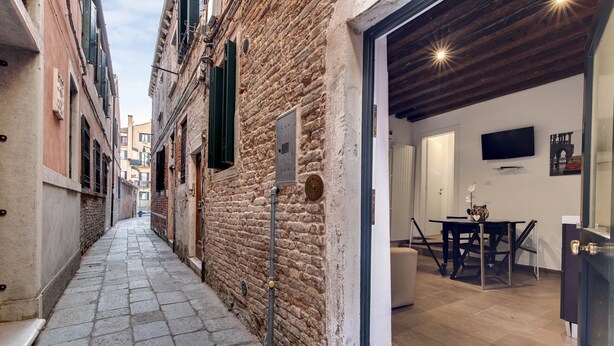 A narrow alleyway with stone paving, a rustic brick wall, and a wooden ceiling. - I Quattro Mori by Wonderful Italy (Venice)