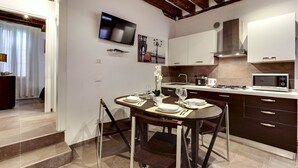 A modern kitchen with dark cabinets, a microwave, and a dining area with a table set for two. - I Quattro Mori by Wonderful Italy (Venice)
