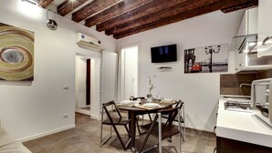 A modern kitchen with a dining area, featuring a wooden ceiling, white walls, and a flat-screen TV. - I Quattro Mori by Wonderful Italy (Venice)