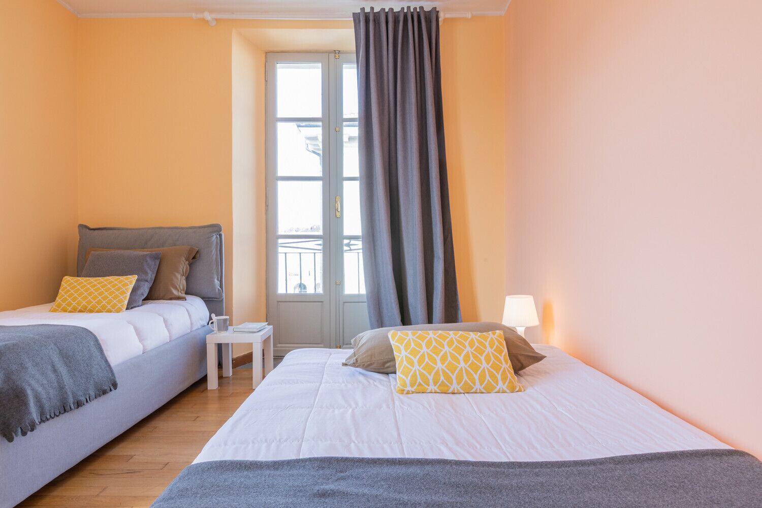 A double room with two beds, a small table, and a window with curtains.