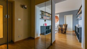 A modern living room with a wooden floor, a glass partition, and a bookshelf. - Vittorio Place by Wonderful Italy (Turin)