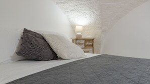 Une chambre à coucher avec un lit, des oreillers, une table de chevet avec une lampe et une commode en bois.
