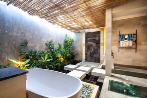 Ein modernes Badezimmer mit einer freistehenden Badewanne, einem kleinen Pool und einer separaten Duschkabine.