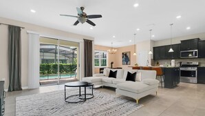 Ein modernes Wohnzimmer mit einer Eckcouch, einem Couchtisch und einem großen Fenster mit Blick auf einen Pool.