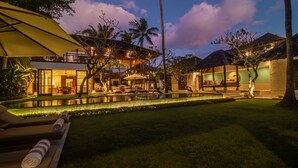 Ein Resort mit Pool, Liegestühlen und einem gut beleuchteten Außenbereich bei Dämmerung.